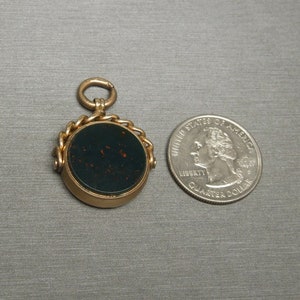 May include: A gold-toned fob seal with a dark green cameo set in a round bezel. The seal is attached to a gold chain and has a loop for attaching to a watch chain.