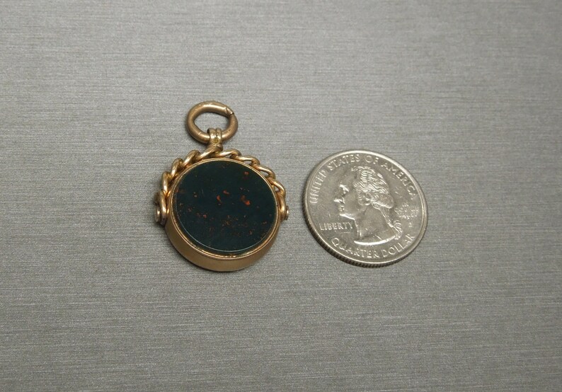 May include: A gold-toned fob seal with a dark green cameo set in a round bezel. The seal is attached to a gold chain and has a loop for attaching to a watch chain.