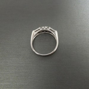 May include: A silver ring with a row of five clear stones set in a channel setting.
