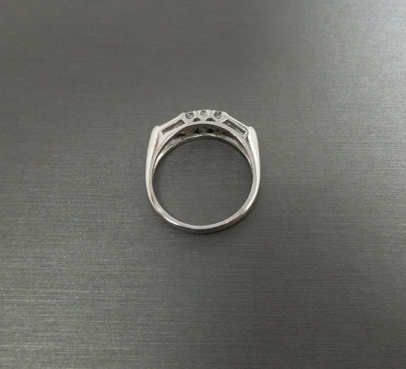 May include: A silver ring with a row of five clear stones set in a channel setting.