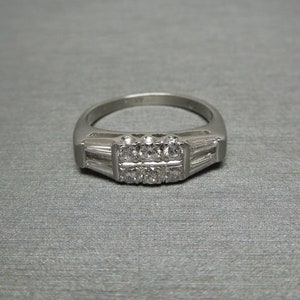 May include: A silver ring with a row of small diamonds set in a band of baguette diamonds.