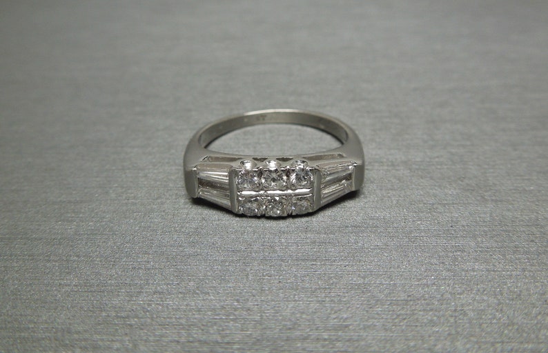 May include: A silver ring with a row of small diamonds set in a band of baguette diamonds.