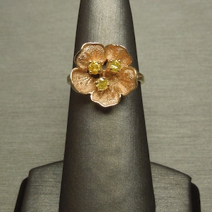 May include: A gold ring with a flower design featuring three yellow gemstones.