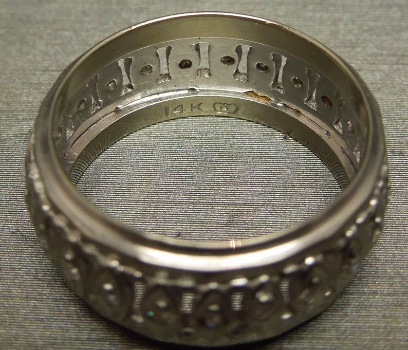May include: A silver ring with a decorative design and the inscription "14K G" on the inside.