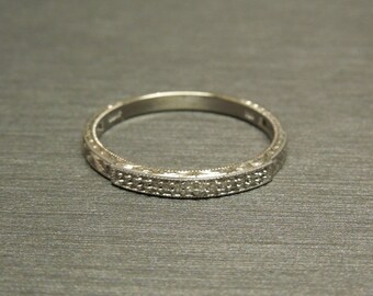 May include: A silver band ring with a row of small diamonds set in a decorative pattern.