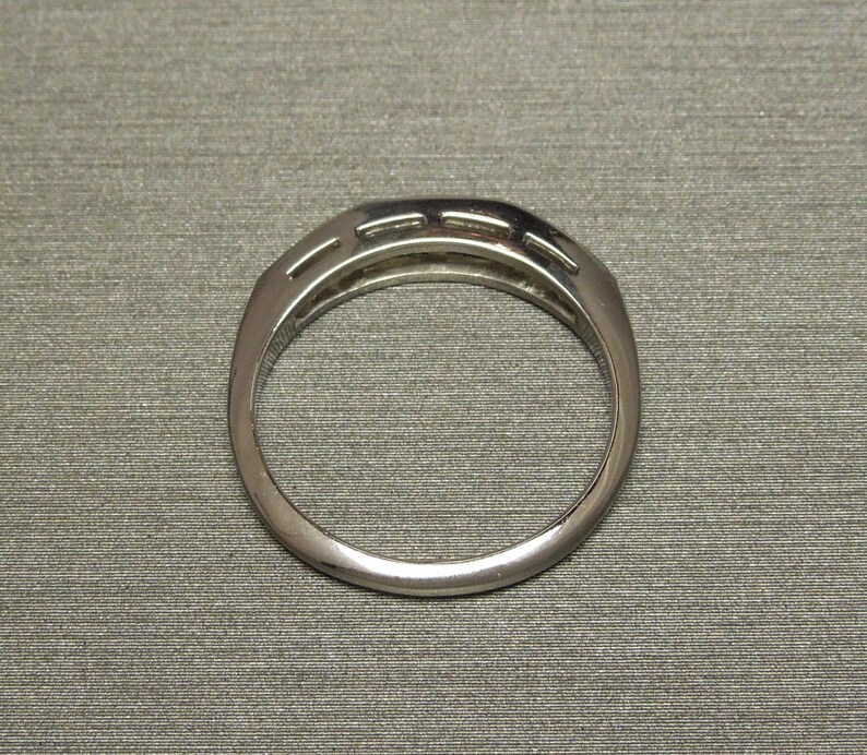 May include: A silver band ring with a row of small diamonds set in a channel setting.