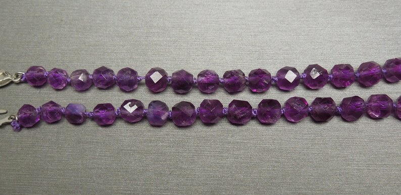 Pode incluir: Duas cordas de contas de ametista roxa enfiadas em um cord&atilde;o roxo com fechos prateados.