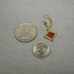 May include: Gold dangle earring with a red square gemstone. The earring is shown next to a US quarter and a US dime for size reference.
