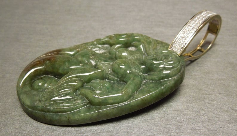 May include: A green jade pendant carved with a detailed design of a dragon, set in a gold pendant with a diamond-encrusted bail.