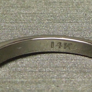 May include: Close-up of the inside of a silver ring with the inscription "14K" on the band.