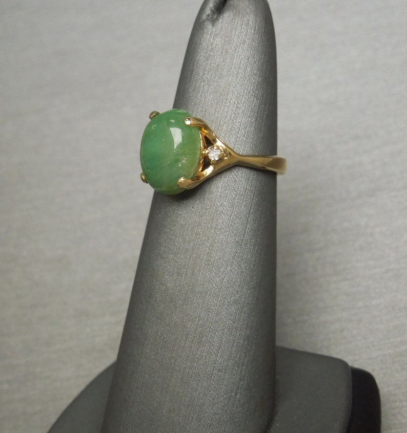 K&ouml;nnte beinhalten: Ein goldener Ring mit einem gr&uuml;nen ovalen Jade-Stein und einem kleinen Diamanten-Akzent.
