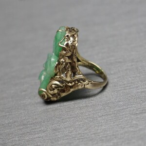 May include: A gold ring with a green jade stone set in a floral design.