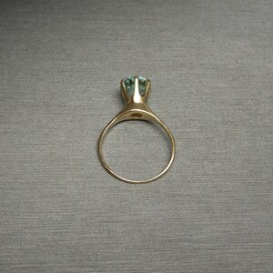 May include: A gold ring with a light blue gemstone set in a prong setting.