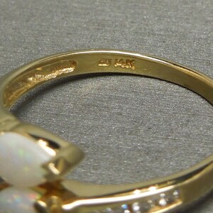 K&ouml;nnte beinhalten: Ein goldener Ring mit zwei birnenf&ouml;rmigen Opalen und einer Reihe kleiner Diamanten. Der Ring ist innen mit "14K" gekennzeichnet.