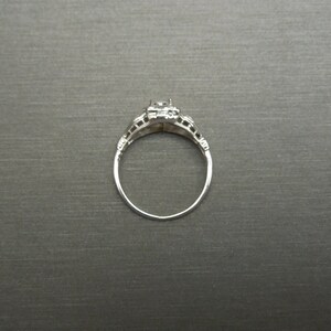 May include: A silver ring with a single, clear gemstone set in a filigree design.