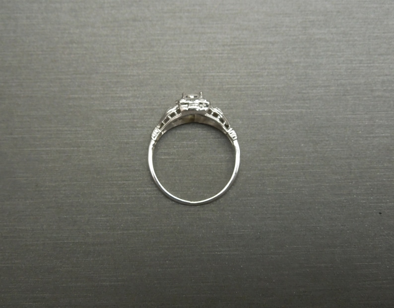 May include: A silver ring with a single, clear gemstone set in a filigree design.