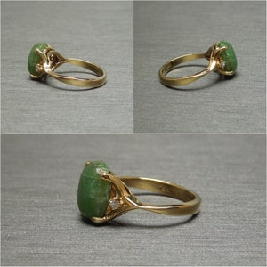K&ouml;nnte beinhalten: Ein goldener Ring mit einem gro&szlig;en gr&uuml;nen Edelstein und kleinen Diamanten, die in die Band gefasst sind.