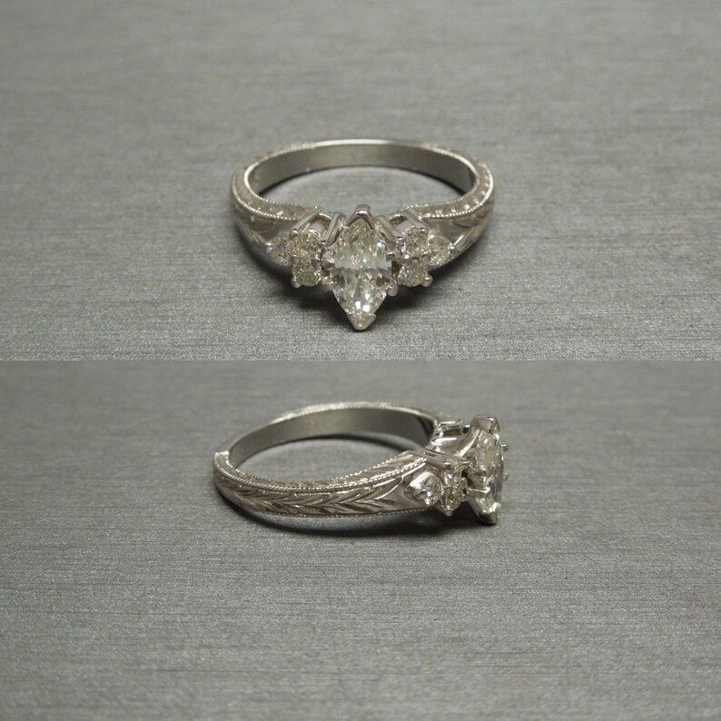 Pode incluir: Uma alian&ccedil;a de noivado de prata com um diamante central em forma de marquise e dois diamantes redondos menores de cada lado. A banda &eacute; decorada com um delicado desenho floral.
