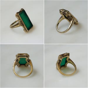 May include: A gold ring with a green rectangular stone set in a filigree design.