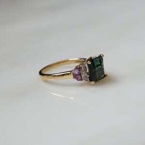 Pu&ograve; includere: Un anello d'oro con una pietra preziosa verde e pietre di accento rosa.