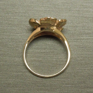 May include: A gold ring with a flower design. The ring is simple and elegant.