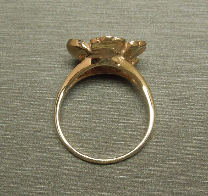 May include: A gold ring with a flower design. The ring is simple and elegant.