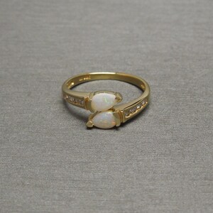 K&ouml;nnte beinhalten: Ein goldener Ring mit zwei birnenf&ouml;rmigen Opalen und einer Reihe kleiner Diamanten.