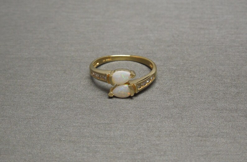 K&ouml;nnte beinhalten: Ein goldener Ring mit zwei birnenf&ouml;rmigen Opalen und einer Reihe kleiner Diamanten.