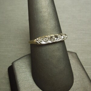 May include: A gold band ring with a heart-shaped design set with small diamonds.