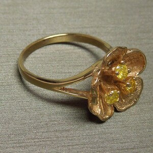 May include: A gold ring with a flower design featuring three yellow gemstones.