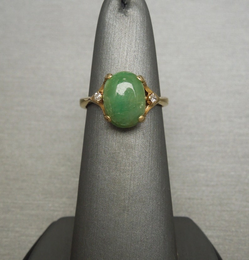 K&ouml;nnte beinhalten: Ein goldener Ring mit einem gr&uuml;nen ovalen Edelstein und zwei kleineren Diamanten.