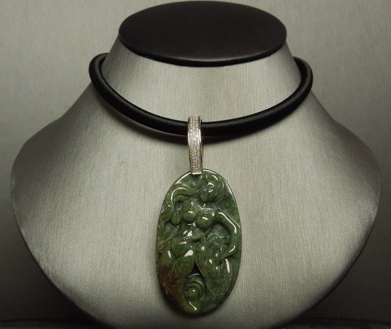 May include: A green jade pendant necklace with a carved figure of a woman. The pendant is set in a gold frame with a diamond-encrusted bail. The necklace is on a black cord.