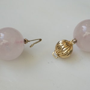 May include: A pink rose quartz beaded necklace with a gold clasp. The beads are large and round.