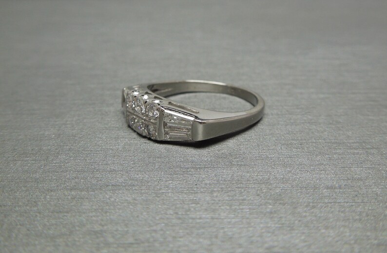 May include: A silver band ring with a row of small diamonds and a row of baguette diamonds.
