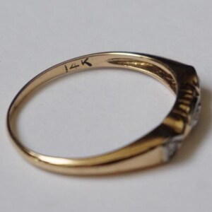 May include: A gold ring with a rectangular face and small, clear stones. The inside of the band is stamped with "14K". The ring is set against a white background.