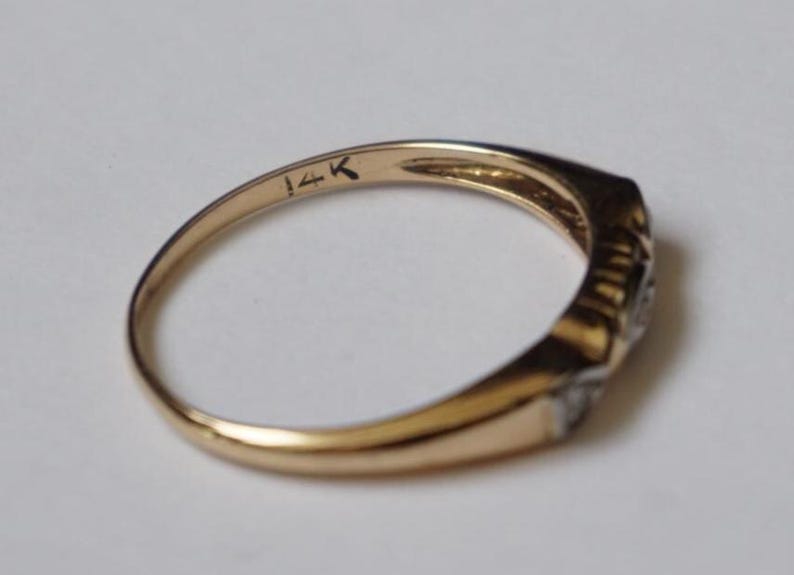 May include: A gold ring with a rectangular face and small, clear stones. The inside of the band is stamped with "14K". The ring is set against a white background.