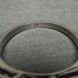 May include: Close-up of the inside of a silver ring with the inscription "14K" on the band.