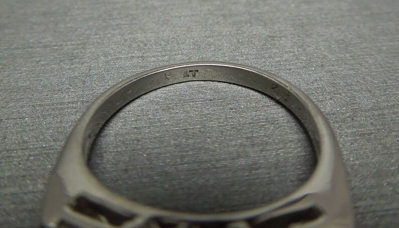 May include: Close-up of the inside of a silver ring with the inscription "14K" on the band.