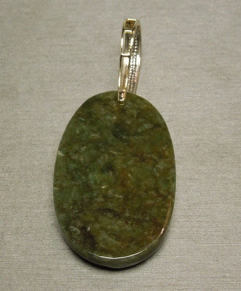 May include: A green oval pendant with a silver bail. The pendant is made of a natural stone with a mottled pattern.