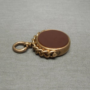 May include: A gold-toned pocket watch fob with a brown carnelian stone and a chain.