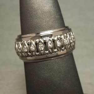 May include: A silver band ring with a row of small diamonds set in a decorative pattern.