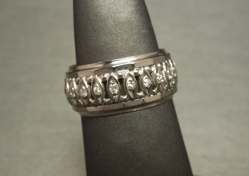 May include: A silver band ring with a row of small diamonds set in a decorative pattern.