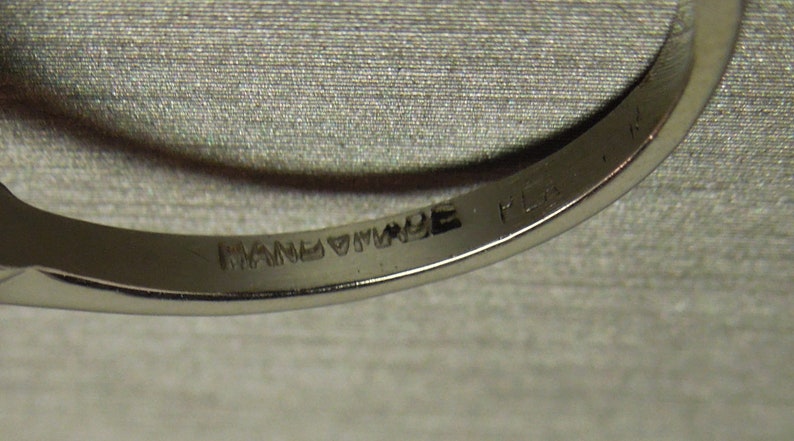 以下が含まれることがあります： 内側に「HANDMADE」と「PLAT. IN」の刻印が施された銀の指輪のクローズアップ。