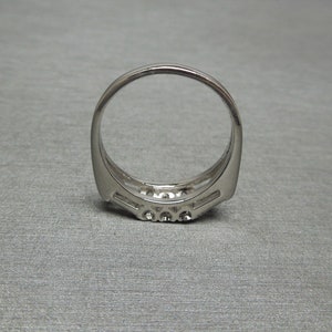 May include: A silver ring with a row of small diamonds set in a curved band.