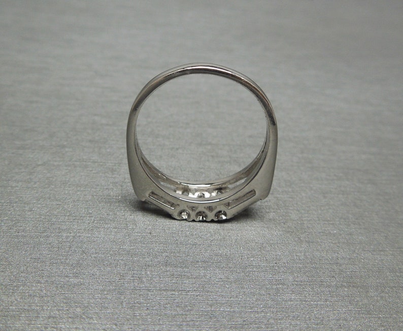 May include: A silver ring with a row of small diamonds set in a curved band.