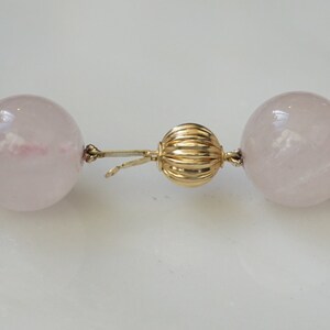 May include: A pink rose quartz necklace with a gold clasp. The necklace is made of large, round beads.