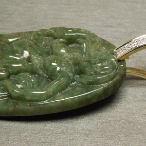 May include: A green jade pendant carved with a dragon design, set in a gold frame with a diamond-encrusted bail.