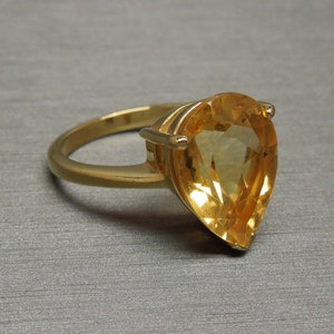 May include: A gold ring featuring a large pear-shaped topaz gemstone.