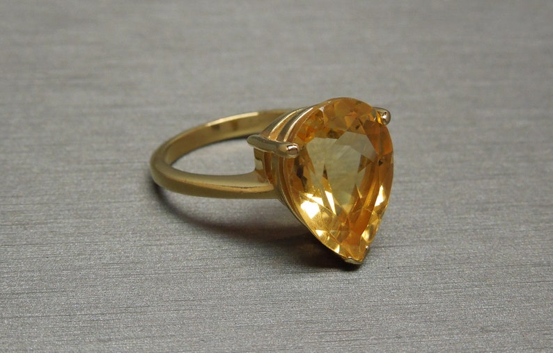 May include: A gold ring featuring a large pear-shaped topaz gemstone.
