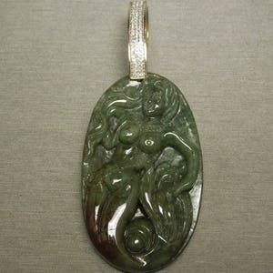 May include: A green jade pendant featuring a carved mermaid with a diamond-encrusted bail.
